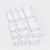 A set of clear plastic rectangular organizer bins in various sizes, arranged on a light gray background.