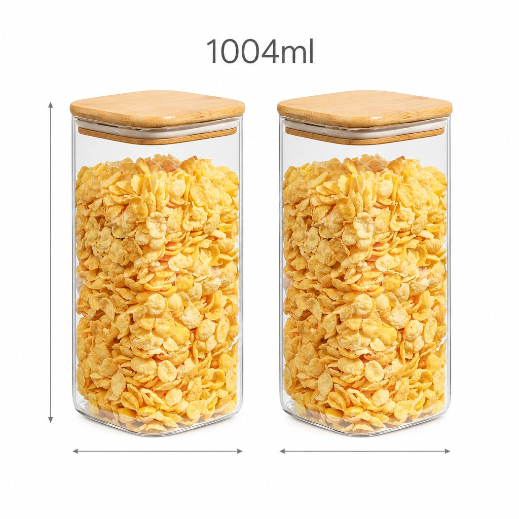 Two clear glass canisters filled with yellow corn flakes, shown side by side on a white background with measurement arrows and the text '1004ml' above. The canisters have light wood lids.