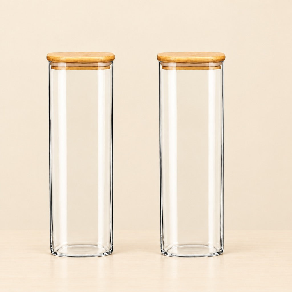 Two tall, clear glass canisters with light brown bamboo lids, standing side-by-side on a light beige surface against a matching beige background.