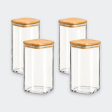 Four clear glass canisters with square bamboo wood lids, arranged in a two-by-two grid on a light gray background.