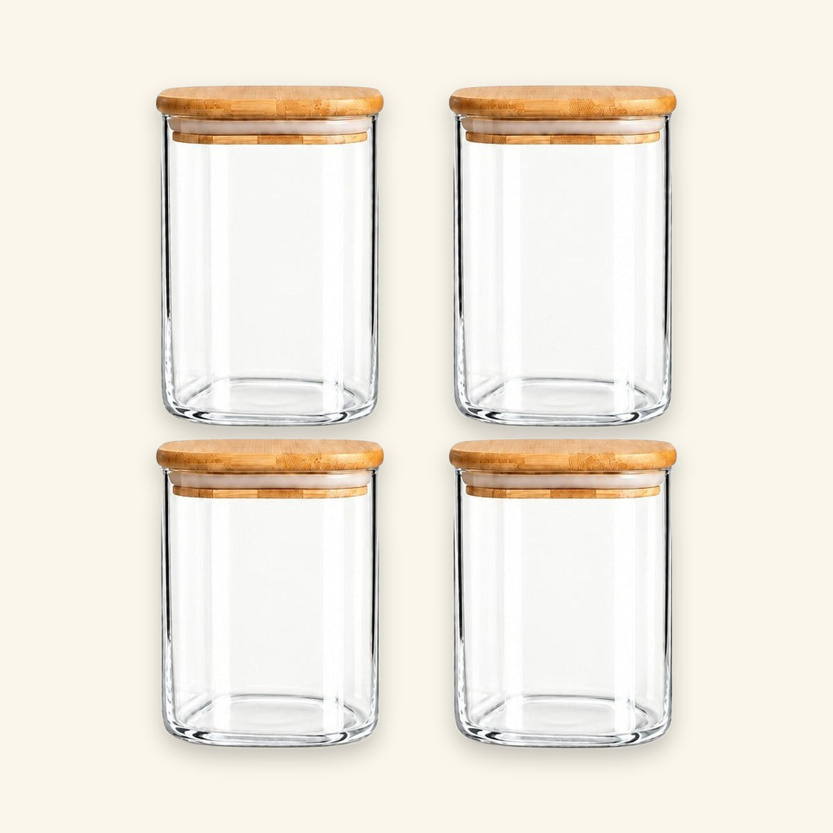 Four clear glass canisters with light brown bamboo lids, arranged in a 2x2 grid on a warm off-white background.