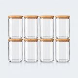 Six clear glass canisters with light brown bamboo lids, arranged in two rows of three against a light gray background.