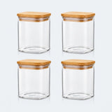 Four clear glass canisters with square bamboo wood lids, arranged in a 2x2 grid on a light gray background.