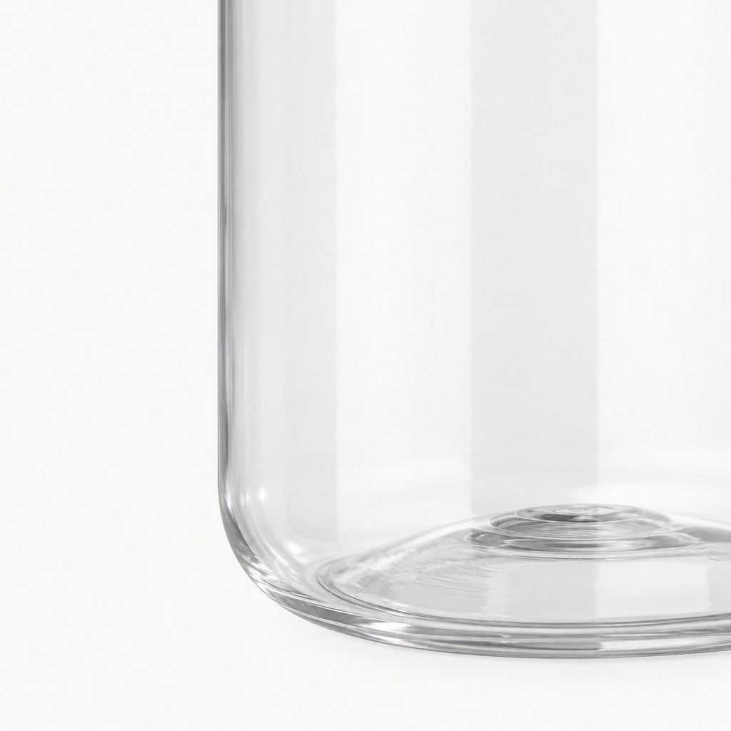 Close-up of a clear glass container or vase showing the lower curved edge and base against a white background.