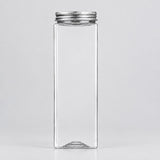 A tall, rectangular clear glass bottle with a silver metal screw cap, shown against a plain light gray background.