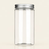 A tall, clear cylindrical plastic jar with a silver metal screw-on lid, shown on a plain light beige background.