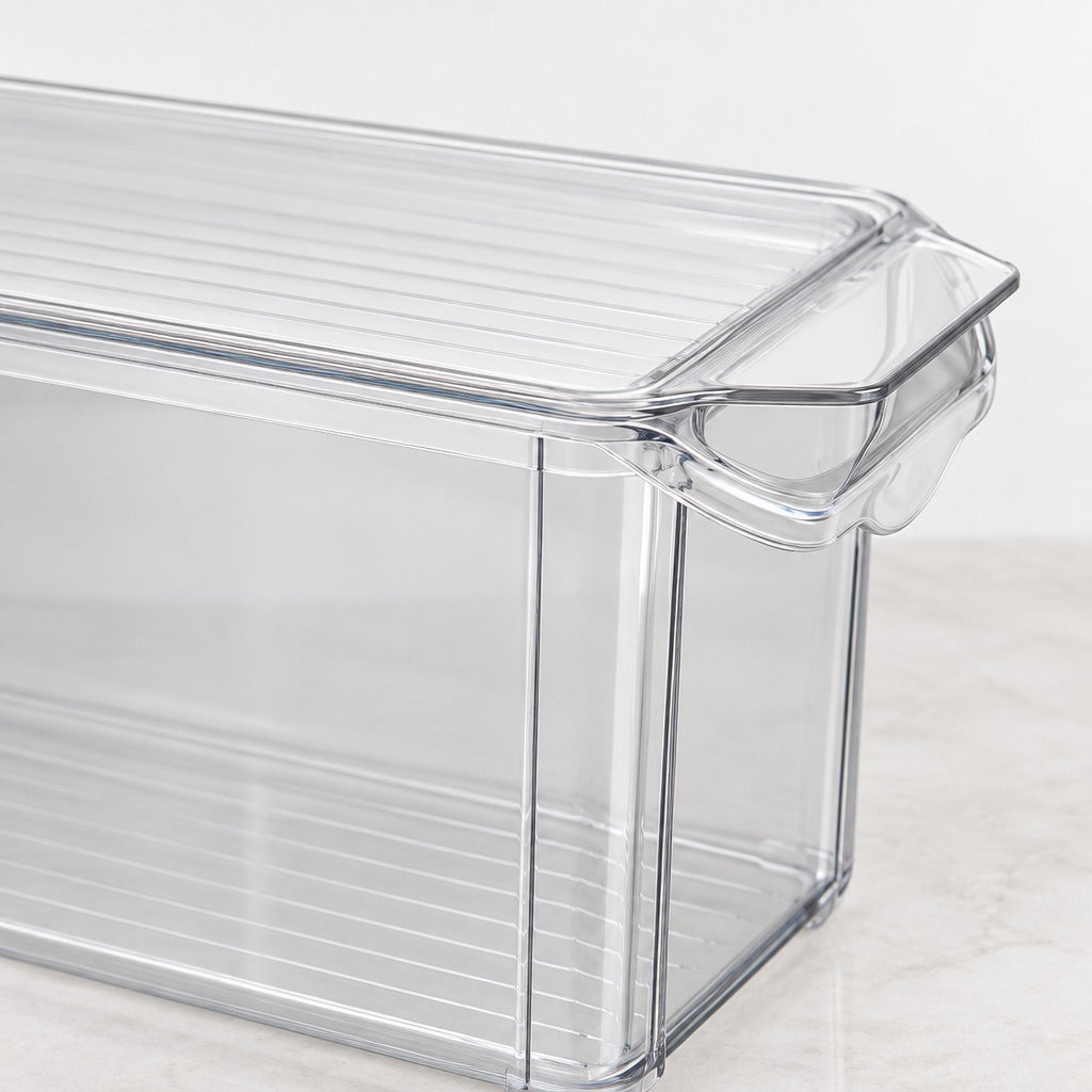 Clear plastic food storage container with a slotted lid and integrated handle, shown on a light marble surface against a white background.