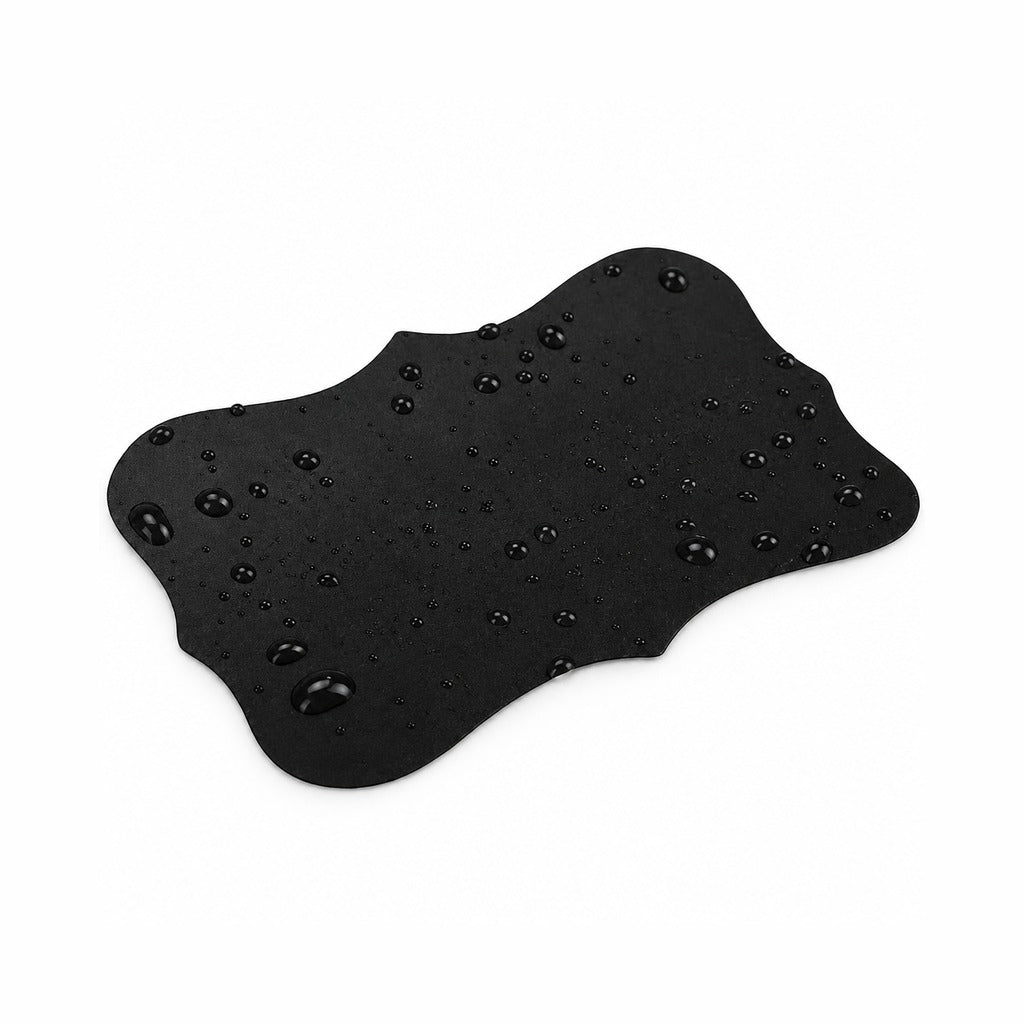 A black, irregularly shaped silicone or rubber pad with a water-repellent finish, covered in small water droplets, shown on a solid white background.