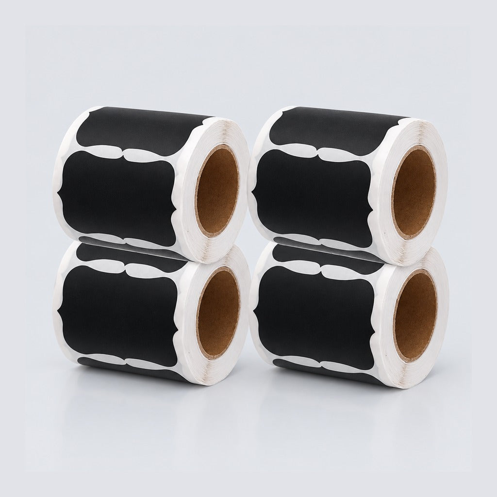 Four rolls of black chalkboard-style labels with white decorative borders and brown cardboard cores, arranged in a 2x2 stack on a light gray background.