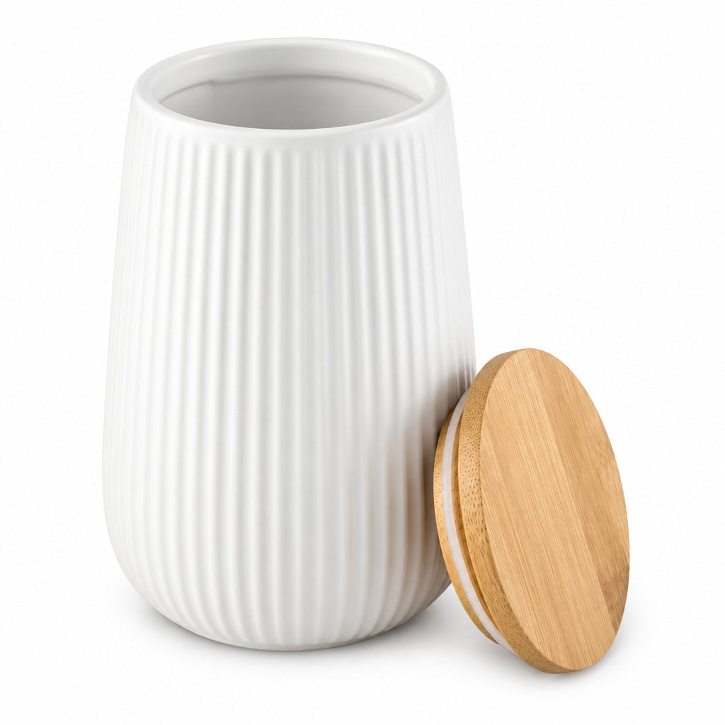 A white ribbed ceramic jar with a matching round bamboo lid leaning against it, photographed on a clean white background.