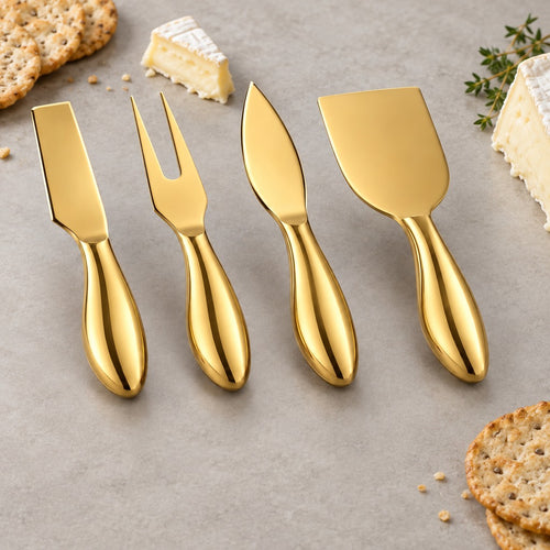 Four gold cheese knives and a fork arranged on a light gray surface with crackers and cheese wedges around them.