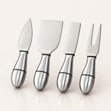 Four stainless steel cheese knives with matching metallic handles, arranged in a row on a light beige background with soft reflections.