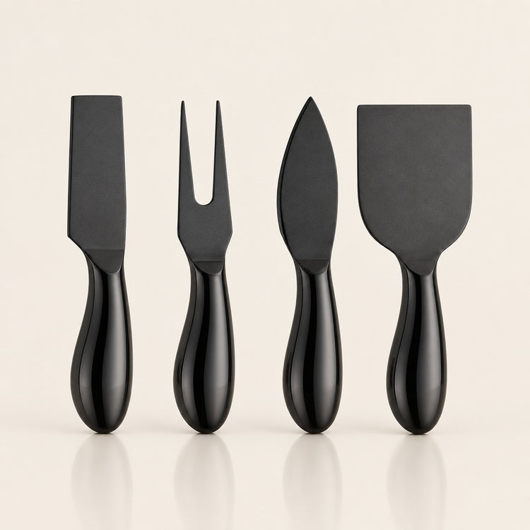 Four black cheese knives with glossy handles, including a flat blade, a two-pronged fork, a spear tip, and a broad spatula, arranged in a row on a light beige background.