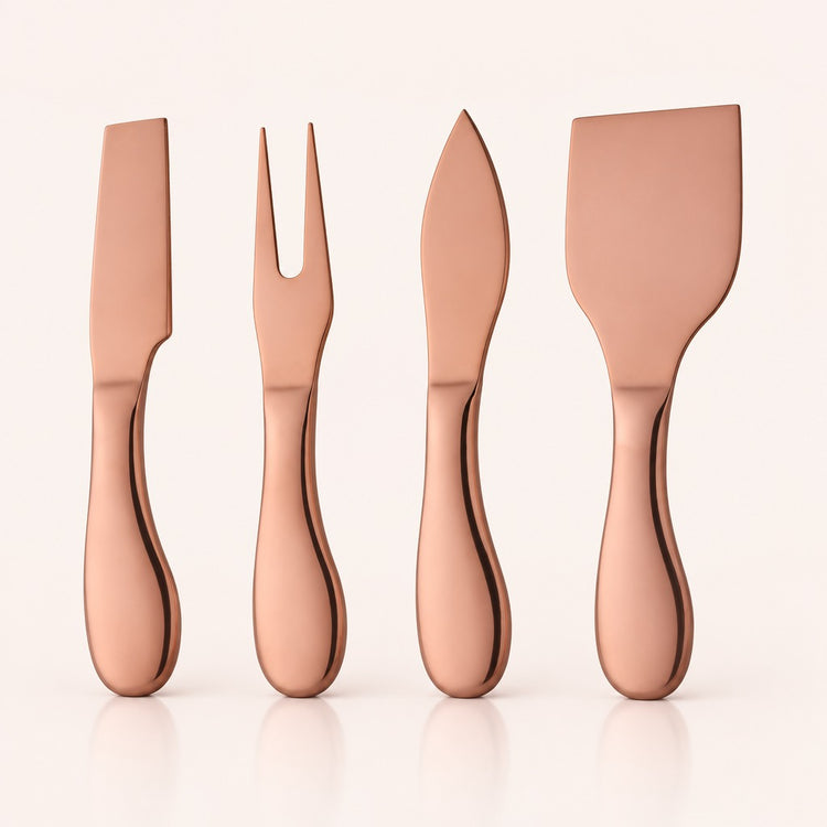 Four metallic cheese knives in a rose gold finish, arranged vertically on a clean off-white background with soft reflections below.