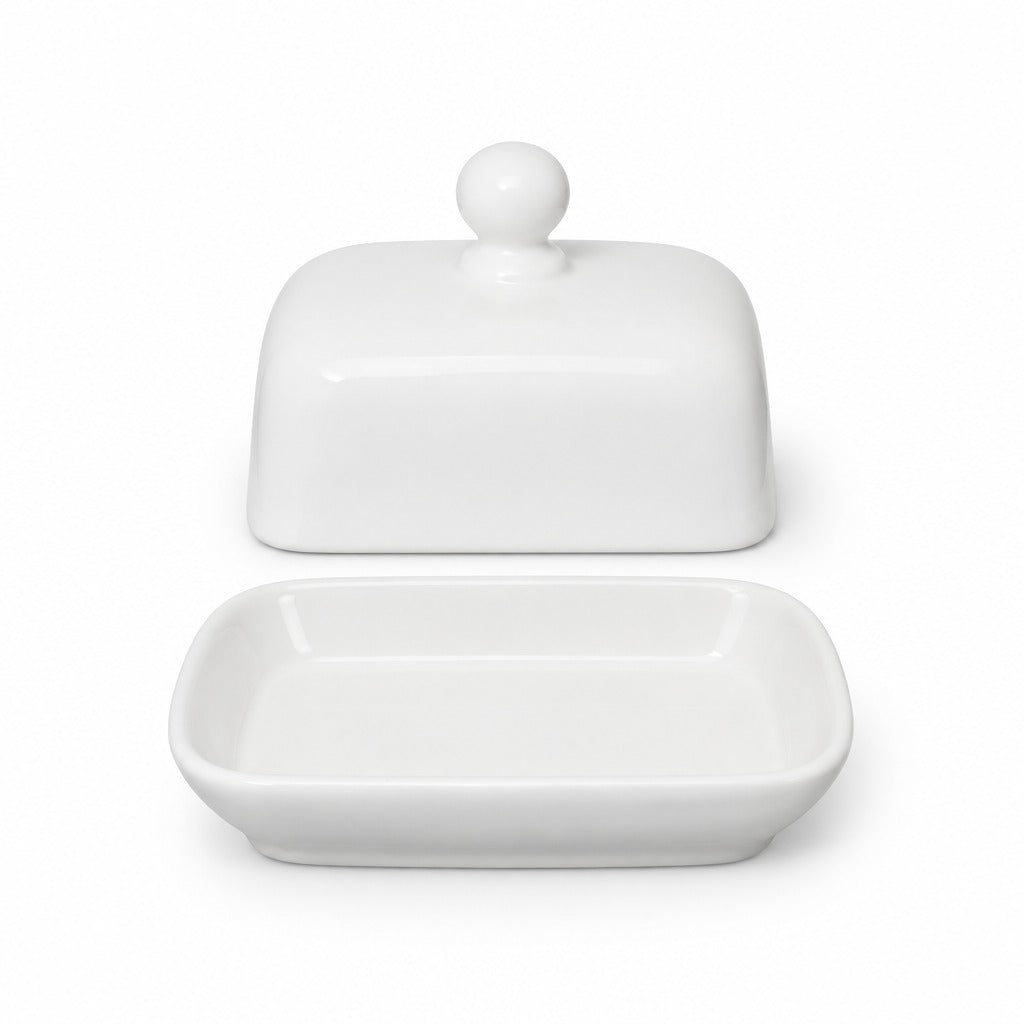 A white ceramic butter dish with its lid off, showing a rectangular tray with rounded corners and a matching rounded lid with a small knob on top, set against a plain white background.