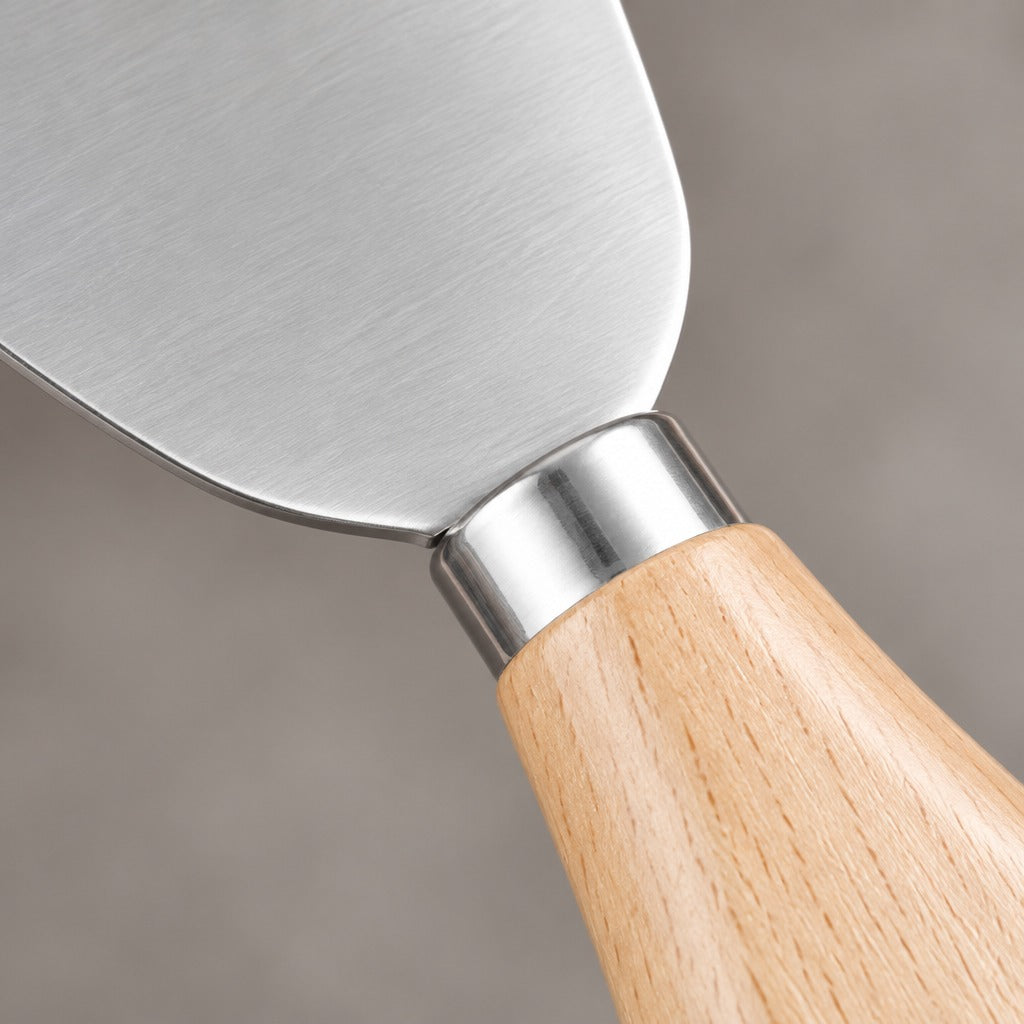 Close-up of a metal trowel or spatula with a brushed silver blade and a light natural wood handle, shown against a soft gray background.