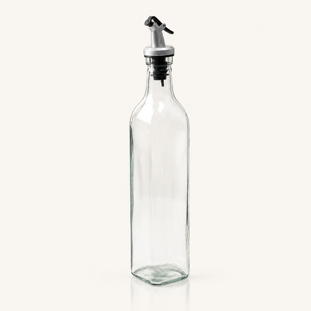 A tall, clear glass bottle with a silver and black metal pour spout, shown on a plain off-white background.
