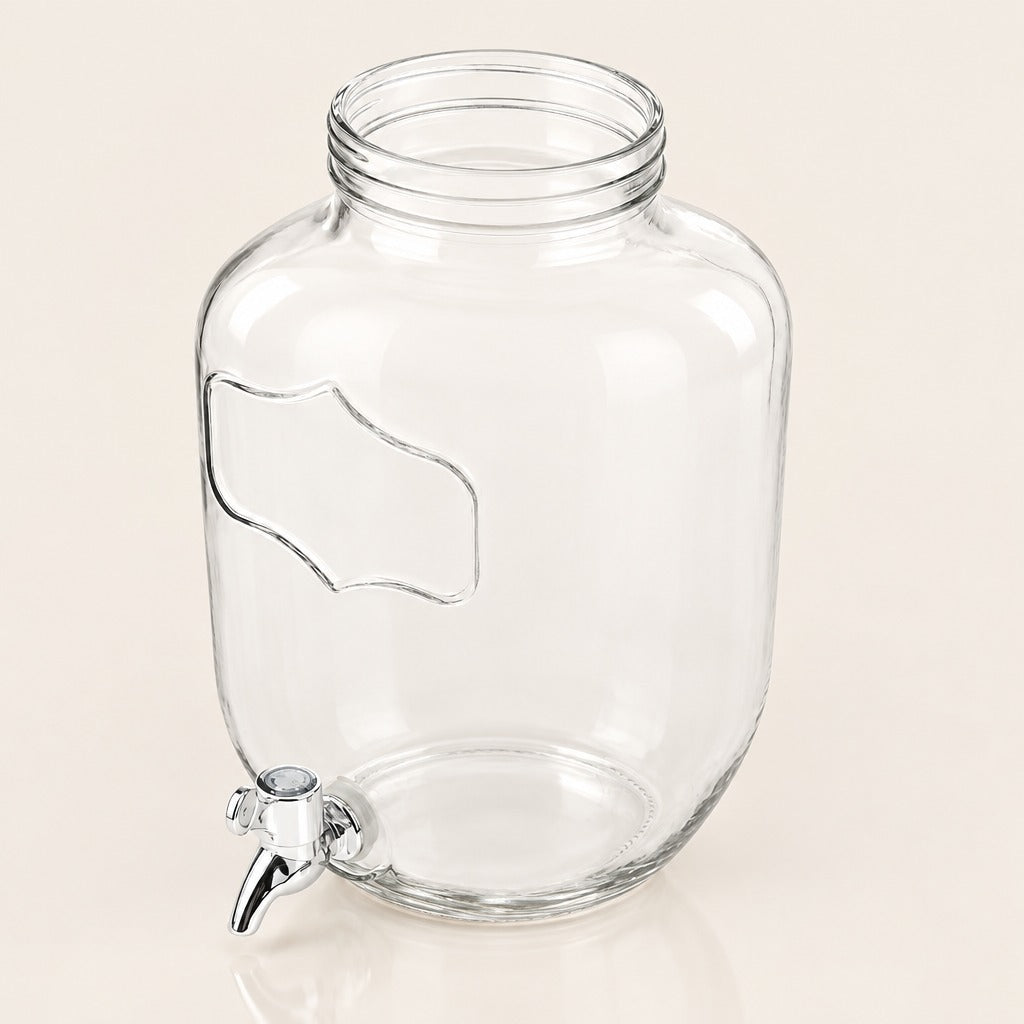 Clear glass beverage dispenser can with a metal spout, photographed on a plain light beige background.