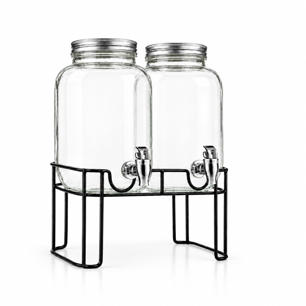 Two clear glass beverage dispensers with silver metal lids and spouts, displayed on a black wire stand with an additional clear measuring cup on a white background.
