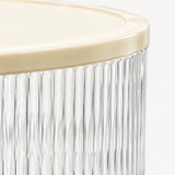 Close-up of a ribbed clear glass container with a cream-colored lid, showing the vertical fluted glass body and a portion of the smooth lid against a white background.