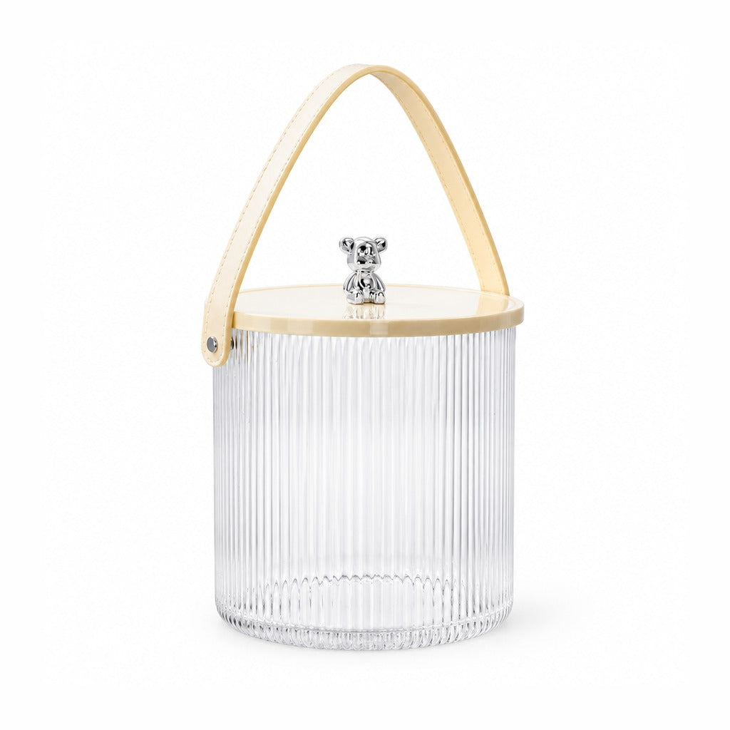 A clear ribbed glass storage bucket with a light natural wood lid, a light wood carrying handle, and a small silver bear figurine on top, shown on a white background.