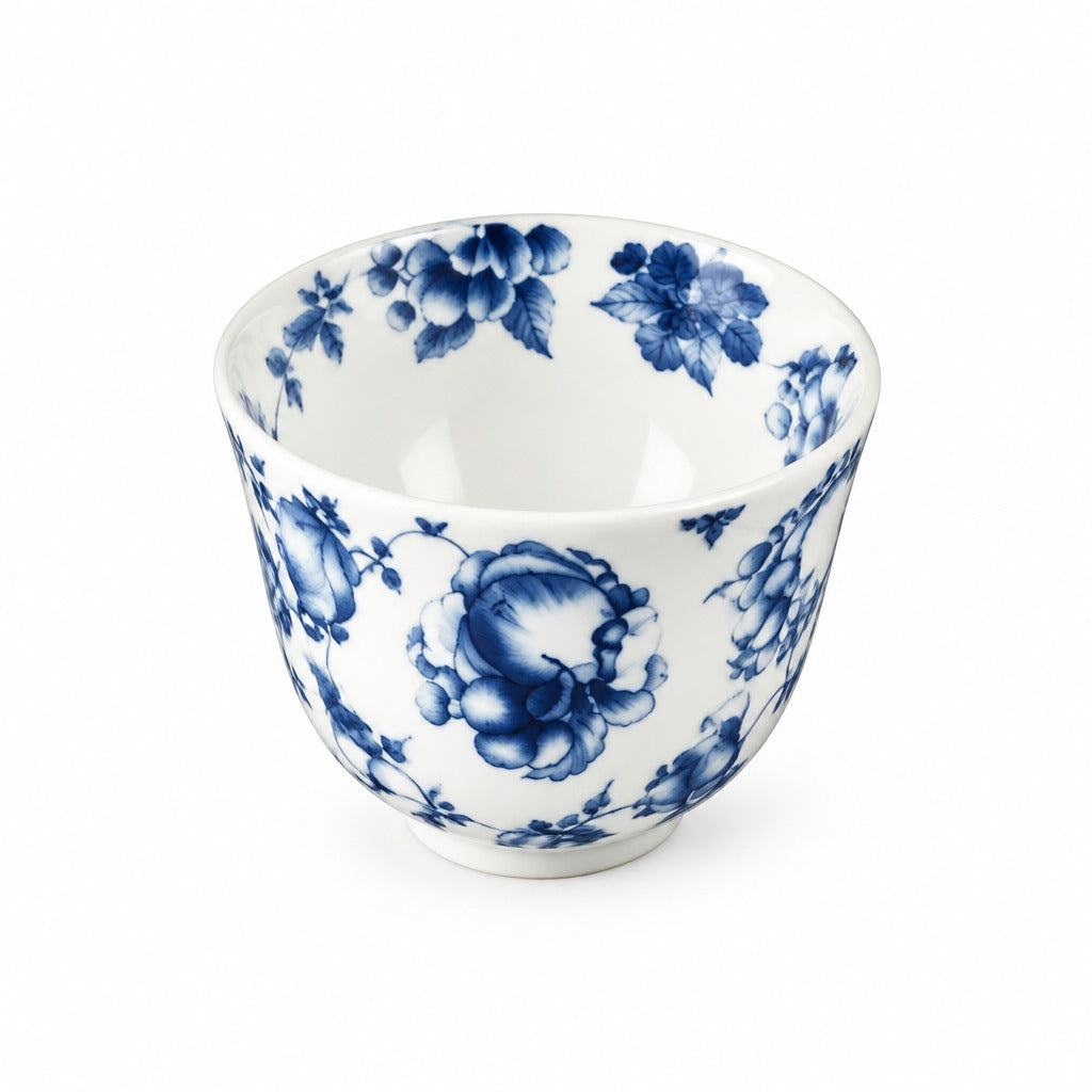 A white ceramic tea bowl decorated with a classic blue floral pattern, photographed against a seamless white background.