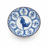 A round ceramic bowl with a blue and white hand-painted design, featuring a rooster in the center and floral motifs around the rim, set against a plain white background.