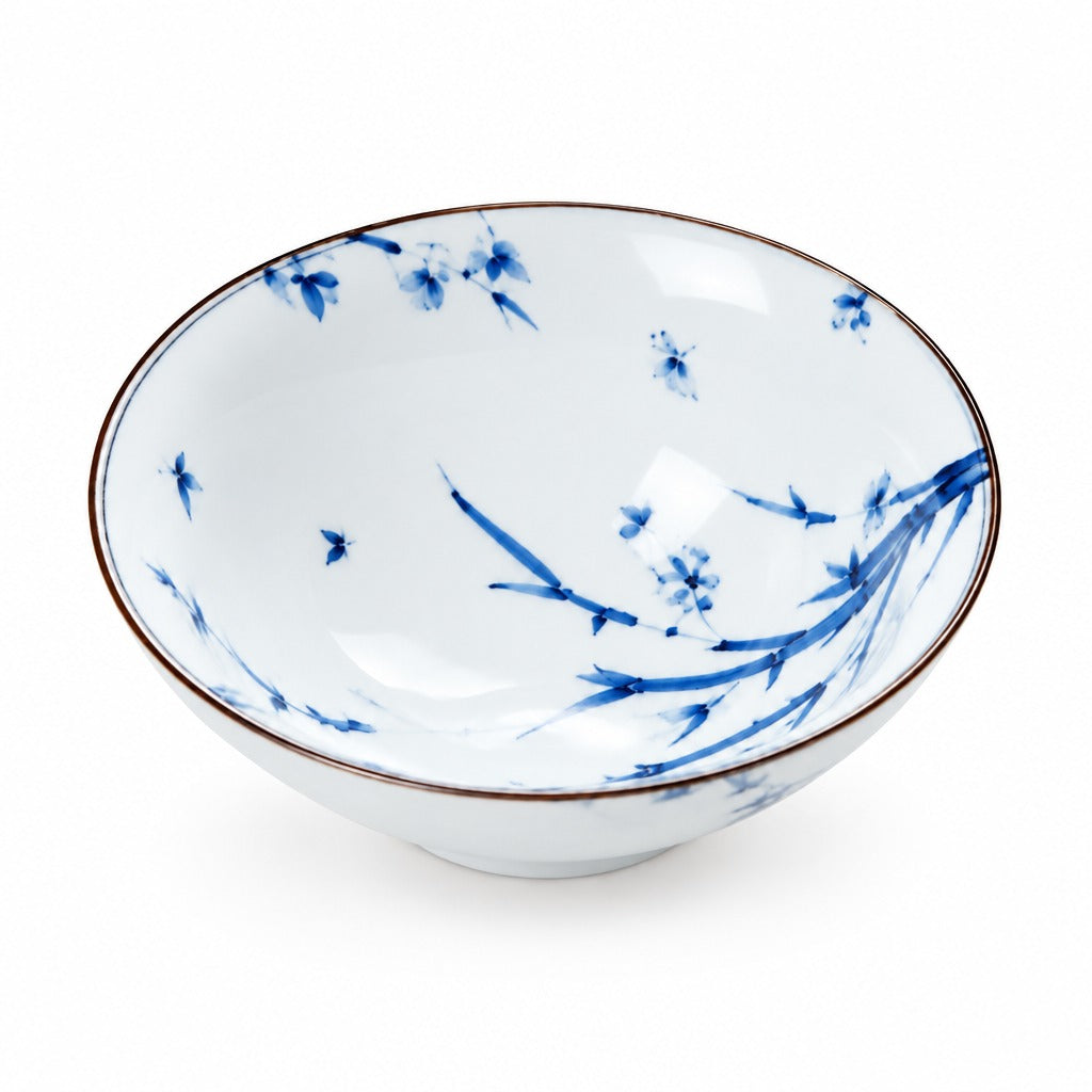 A white ceramic bowl decorated with blue floral and branch motifs, featuring a thin brown rim, shown on a clean white background.