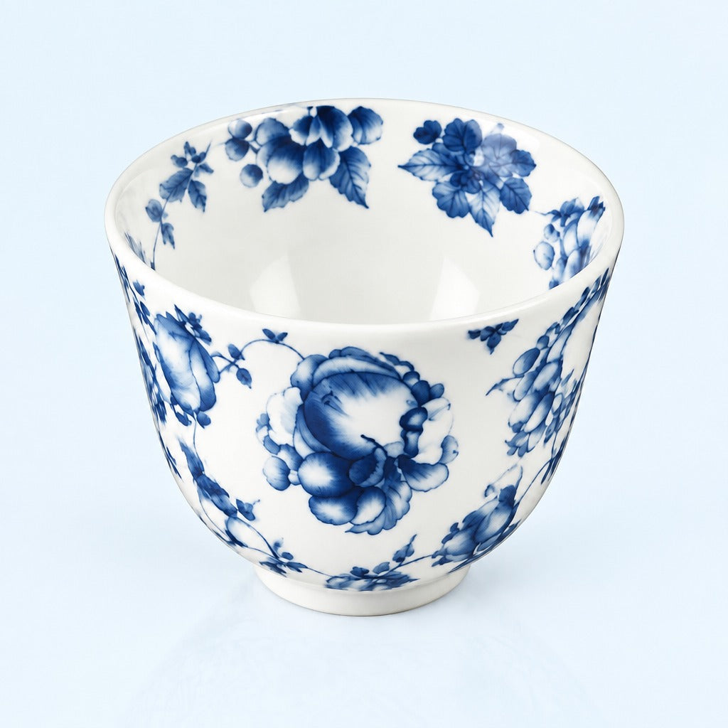 A white ceramic bowl decorated with a classic blue floral pattern, photographed against a light blue background.