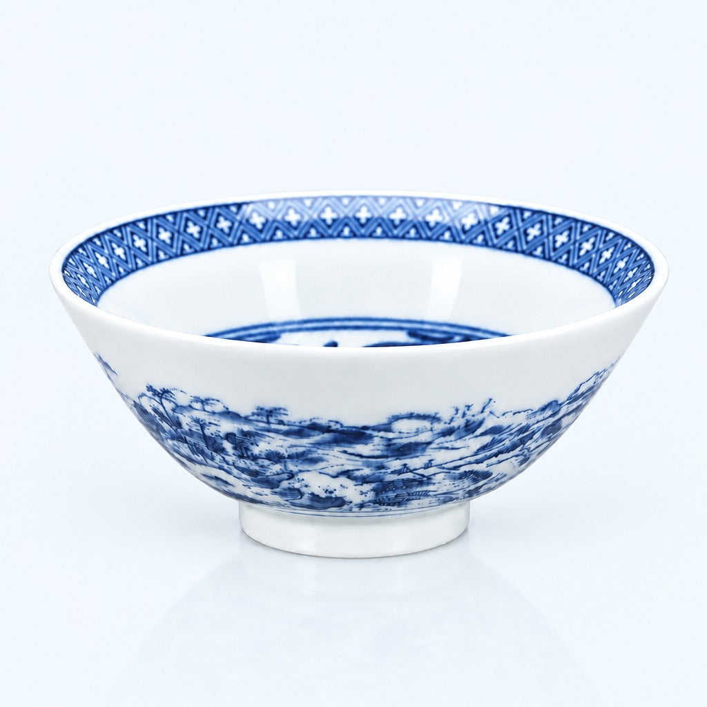 A white ceramic bowl with blue hand-painted traditional patterns, including a geometric border on the rim and a scenic landscape design on the exterior, set against a clean white background.