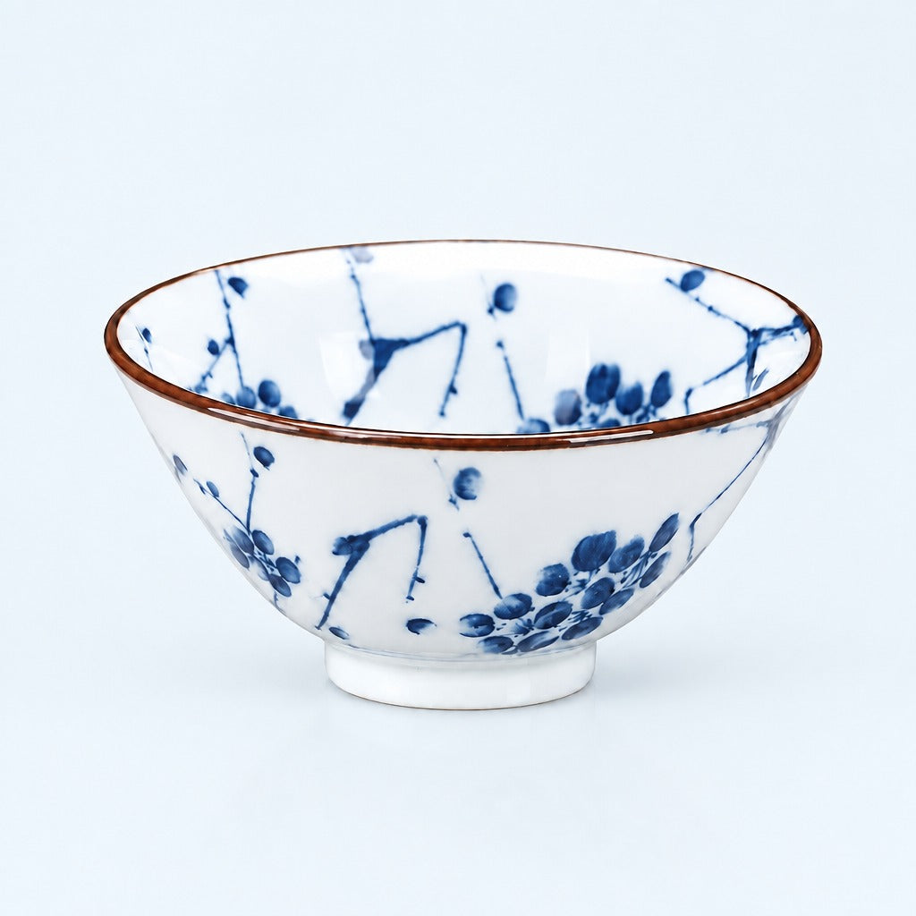 A white ceramic bowl decorated with blue floral brushstroke patterns and a thin brown rim, shown against a light blue background.