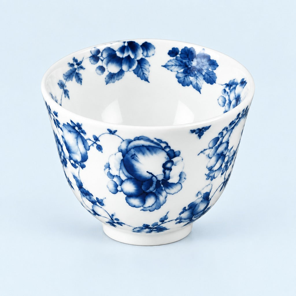 A white ceramic bowl decorated with a classic blue floral pattern, photographed against a solid light blue background.