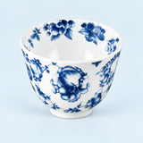 A white ceramic bowl decorated with a classic blue floral pattern, photographed against a solid light blue background.