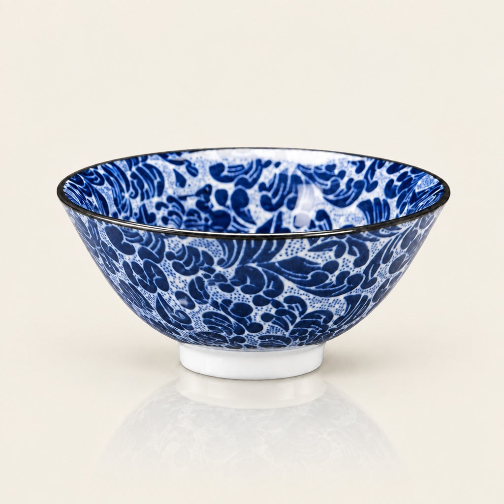 A blue and white patterned ceramic bowl with a black rim, shown on a clean off-white background with a soft reflection underneath.