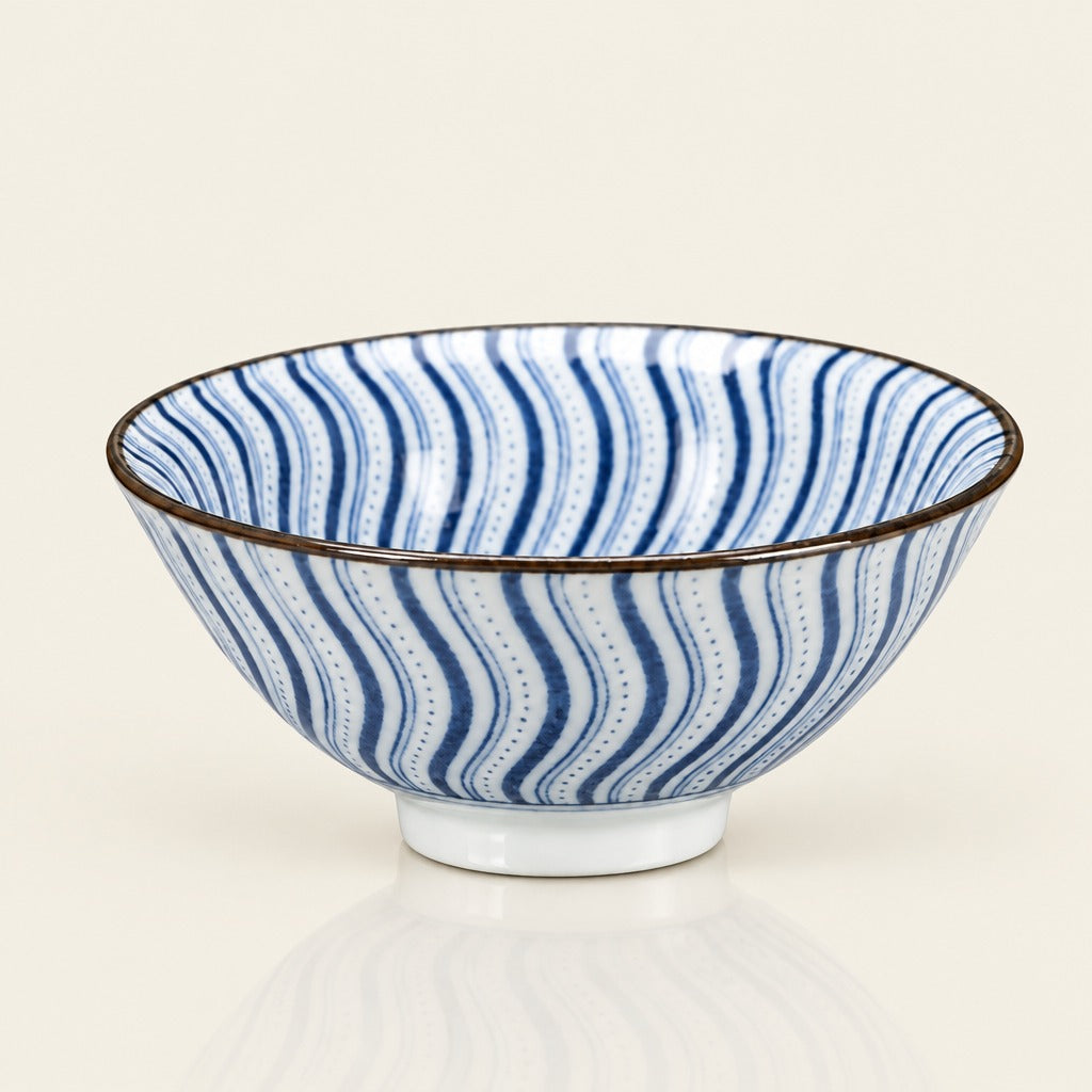 A ceramic bowl with a blue and white wavy stripe pattern and a dark rim, shown on a clean off-white background with a soft reflection below.