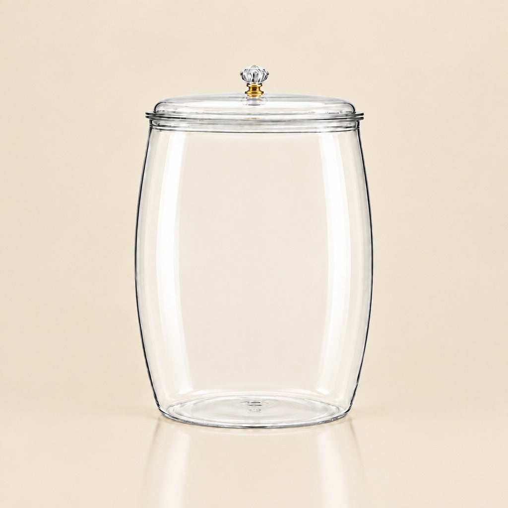 A clear glass canister jar with a matching glass lid and a small gold-toned knob, shown on a warm beige background.
