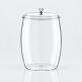 Clear glass canister jar with a matching glass lid and a small silver-toned decorative knob on top, shown on a light gray studio background.