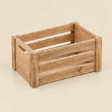 A miniature wooden crate with a slatted design and a small cutout handle on one side, shown on a plain beige background.