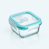 A square clear glass storage container with a translucent aqua blue silicone lid seal and handle, shown on a clean white background.