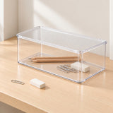 Clear plastic storage organizer box with a slatted lid, shown on a light wood tabletop in a bright indoor setting.