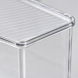 Close-up of a transparent acrylic side table with a slatted top and clear legs on a light gray background.