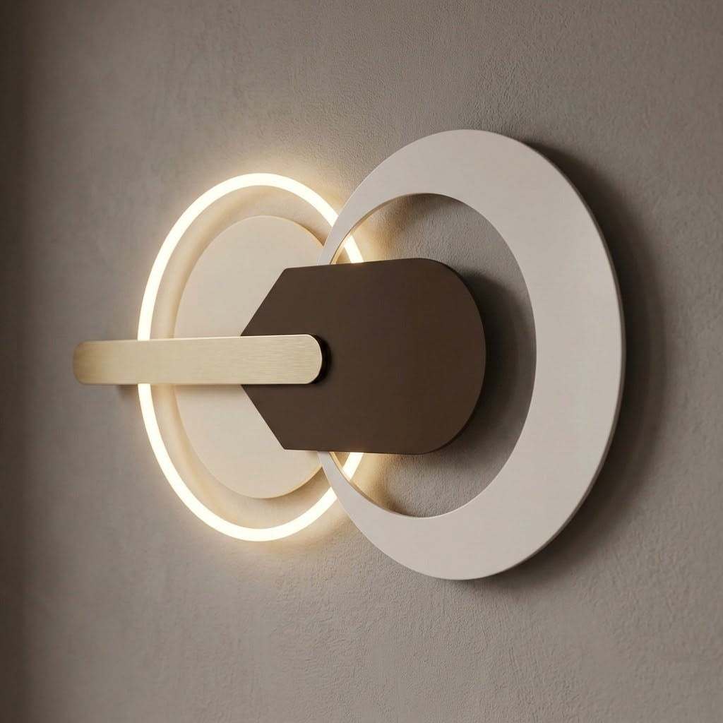Modern wall-mounted light fixture with two overlapping circular rings, one glowing warm white, a white outer ring, a dark brown central panel, and a horizontal cream bar against a textured gray wall.