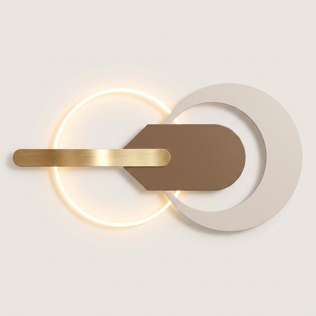 Modern wall sconce with a glowing circular light, a horizontal brushed gold bar, and overlapping matte white and taupe geometric shapes on a light neutral background.