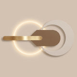 Wall light with overlapping white and illuminated circular forms, a taupe central plate, and a gold-tone horizontal bar against a beige background.