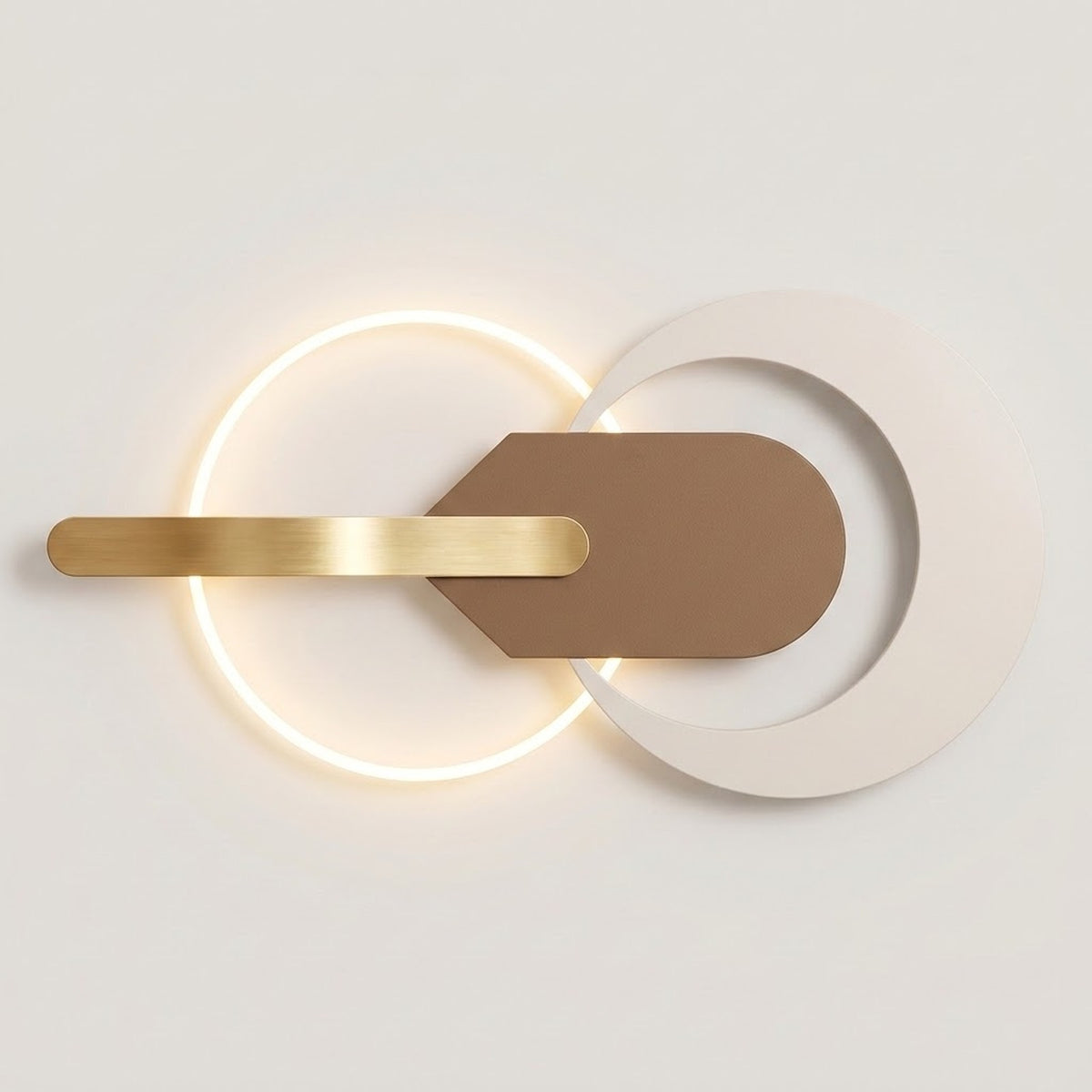 Modern wall sconce with a glowing circular LED light, a brushed gold horizontal bar, and a matte taupe geometric shield overlay on a white circular plate, shown against a neutral off-white background.