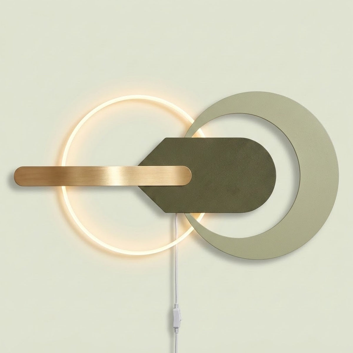 Modern wall-mounted light fixture with a glowing circular ring, a large matte off-white circular cutout, a dark olive green geometric center, and a horizontal brushed brass bar, shown against a pale beige wall.