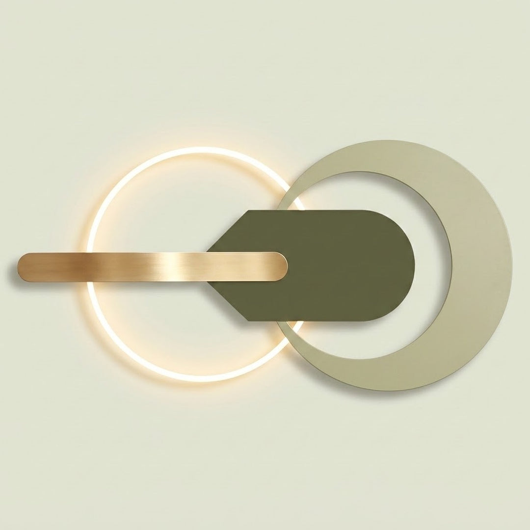 Modern wall sconce with a glowing circular ring, a matte olive green arrowhead shape, and a brushed brass bar on a light beige background.