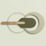 Abstract geometric wall art featuring overlapping circular and curved shapes in muted sage green, warm beige, and light wood tones against a pale cream background.