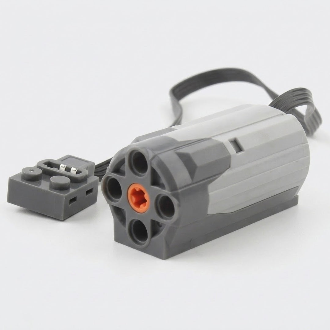 A gray plastic building block motor component with an orange axle socket, black cable, and gray connector rests against a white background.