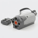 A gray plastic building block motor component with an orange axle socket, black cable, and gray connector rests against a white background.